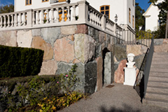 Stenmur i natursten och stentrappa i granit